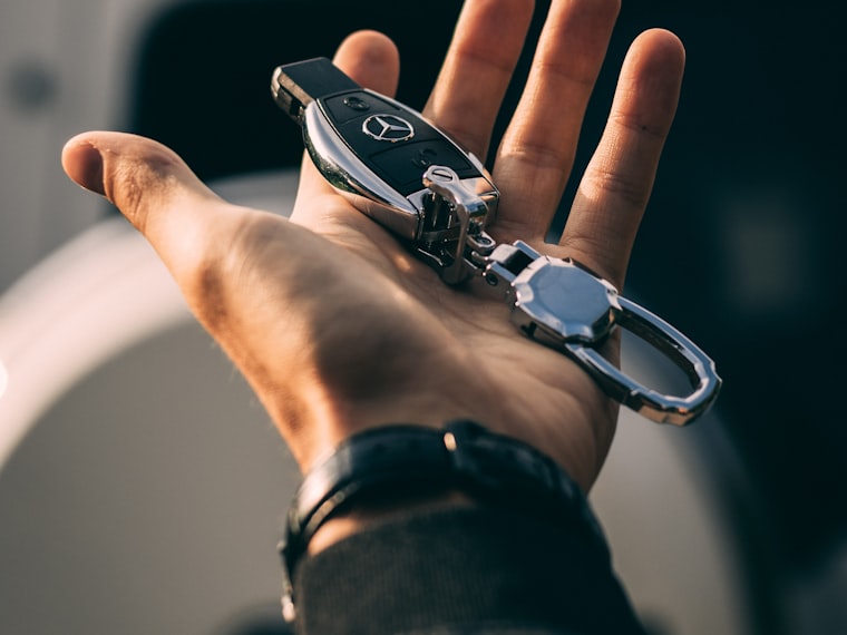 An open hand holding a car key fob with its keyring